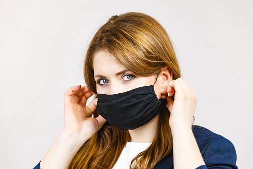 Business woman using protective face black mask against coronavirus. Corona virus prevention, preventive gear.