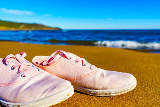 istock Female sneakers on sand beach 1408104040