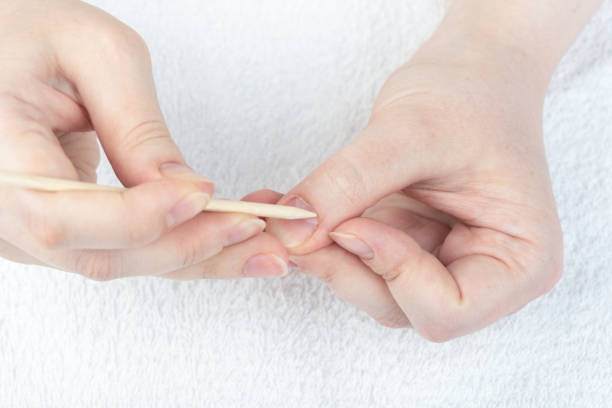 istock A woman corrects the cuticle on her hand with an orange stick. 1408106379