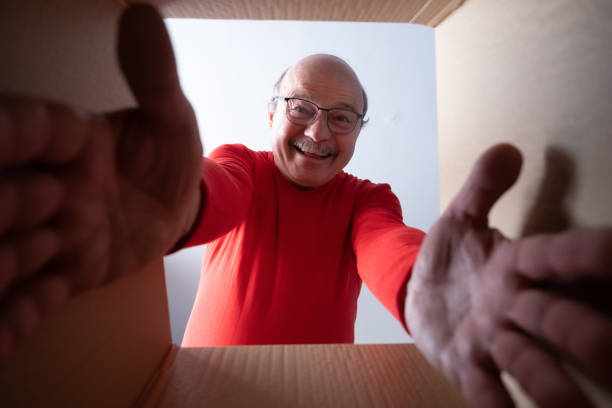 istock Senior surprised man unpacking, opening carton box and looking inside. 1408107977