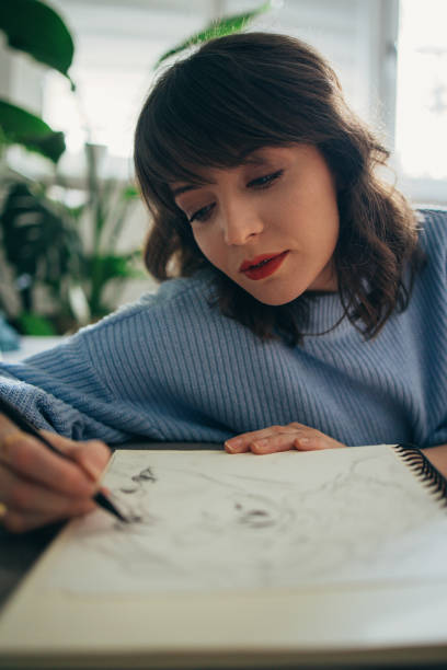 istock Serious Woman Drawing Sketch In Her Notebook At Home 1408110205