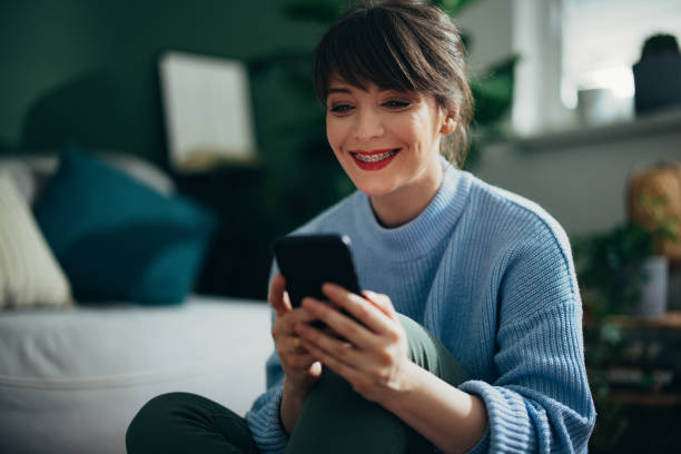 istock Smiling Woman Using Mobile Phone At Home 1408110244