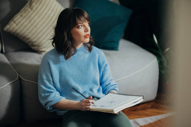istock Beautiful Woman Drawing Sketch In Her Notebook At Home 1408110267