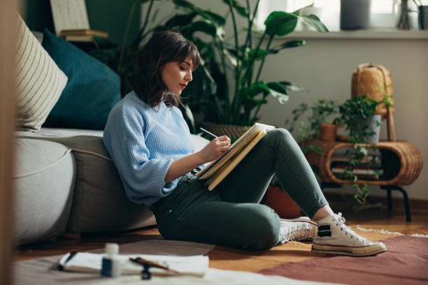 istock Beautiful Woman Drawing Sketch In Her Notebook At Home 1408110276