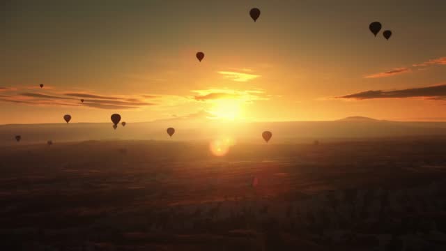 Landscape of amazing golden sky illuminated by sun going down and levitating balloons in the air