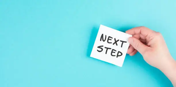The phrase next step is standing on a paper, having new goals and strategies, making plans for future