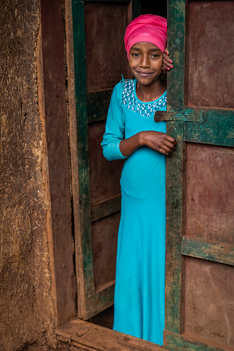 African young girl looking outside her house in a remote village, Central Ethiopia, East Africa