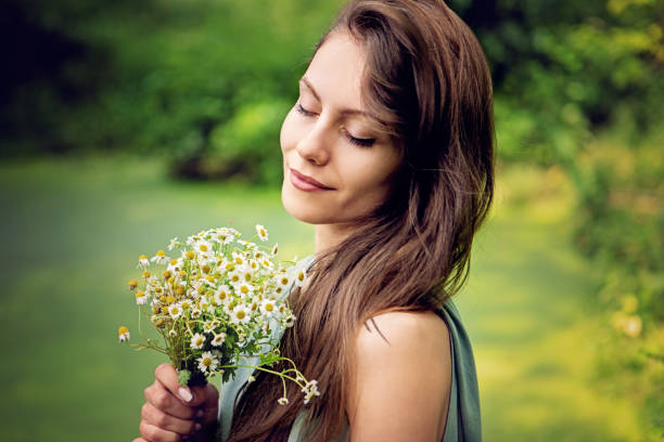 ritratto di giovane donna che tiene un bouquet di camomilla - german chamomile chamomile plant smelling flower foto e immagini stock