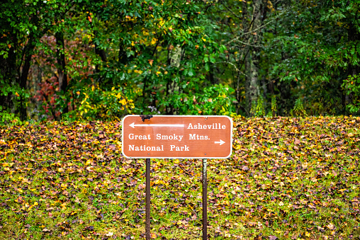 Blue Ridge mountains national park in autumn fall with yellow green foliage leaves and sign on parkway for road directions to Asheville and Great Smoky mountains