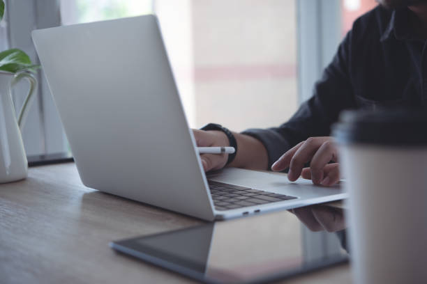 istock Close up of business man using, typing on laptop computer keyboard, online working from home office with digital tablet on wooden table 1408126937