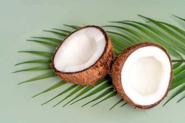 istock Coconut halfs, tropical leaf on green background. Close-up. Spa, organic cosmetics concept. 1408127736