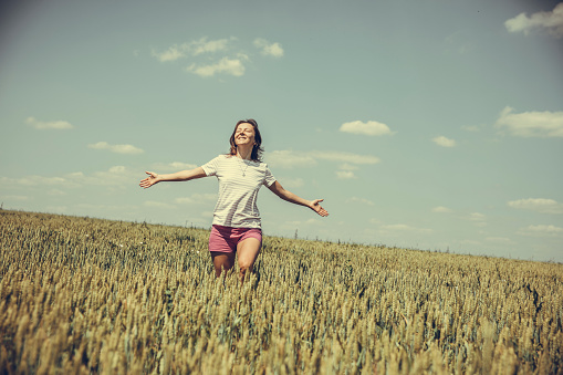 Mid adult woman enjoyng freedom in the wheat field on a summer day