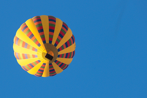 Looking up from underneath a hot air balloon in flight with a blue sky.