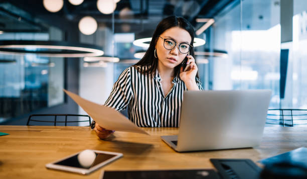 istock Focused Asian woman talking on phone in cafe 1408134249