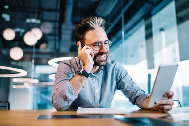 istock Happy businessman with tablet talking on phone 1408134251