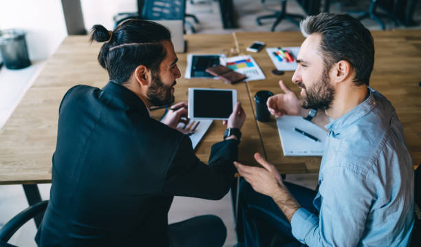 Businessmen discussing new project and surfing tablet in workplace