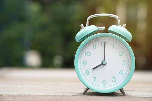 Retro alarm clock on wooden table background, vintage style.