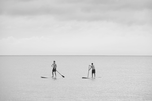 Rehoboth Beach, USA - July 3, 2022. Two men paddle boarding on sea at Rehoboth Beach, Delaware, USA