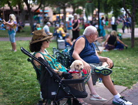 Santa Fe, NM: A senior couple with a toy poodle relaxing on the Santa Fe Plaza on a summer evening.