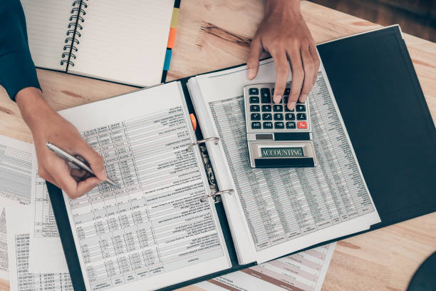 Investors working on desk office and using a calculator to calculate balance, profit, currency and cost. Accounting and  Financial concept. stock photo