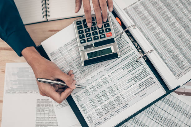 Investors working on desk office and using a calculator to calculate balance, profit, currency and cost. Accounting and  Financial concept. stock photo