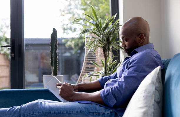 istock Man relaxing at home reading a book 1408150645