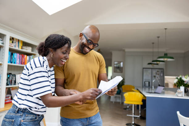 Excited couple reading a letter in the mail with good news Excited African American couple reading a letter in the mail with good news and smiling - domestic life concepts opening event stock pictures, royalty-free photos & images