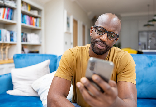 Man relaxing at home looking at social media on his cell phone