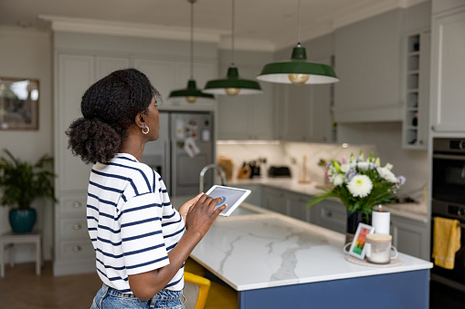 African American woman controlling the lights in their house using an automated system - smart home concepts