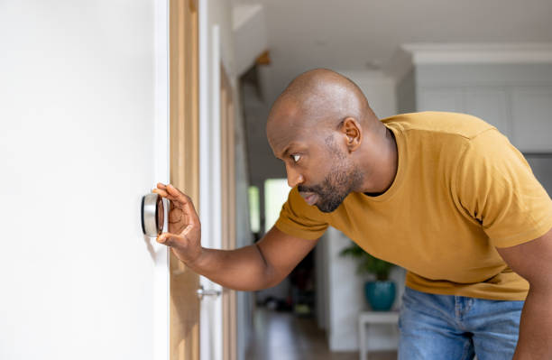 hombre ajustando la temperatura en el termostato de su casa - termostato fotografías e imágenes de stock