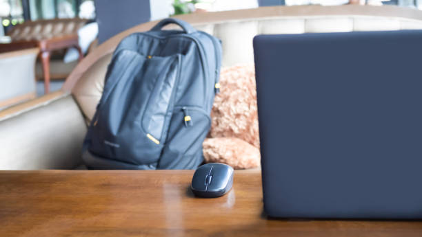 istock Mouse with blur laptop computer on wooden table and blur backpack on sofa 1408151447