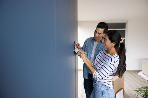 Loving newlywed couple having fun choosing a color to paint the walls of their house