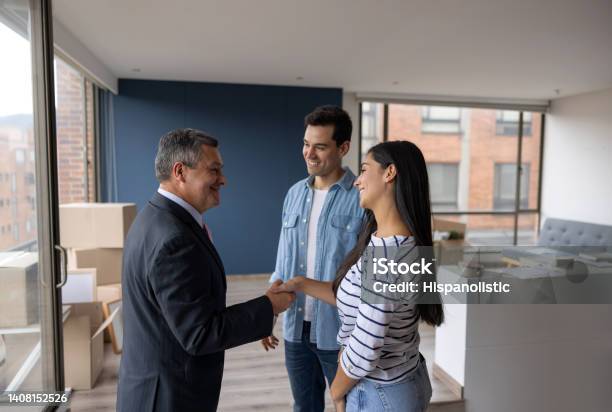 Real Estate Agent Selling An Apartment To A Couple And Closing The Deal With A Handshake Stock Photo - Download Image Now