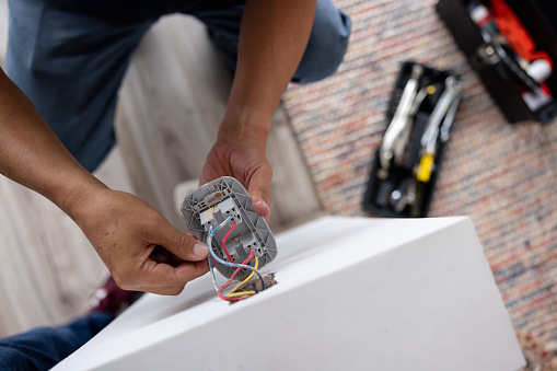 Close-up on a repairman fixing an electrical outlet - electricity concepts