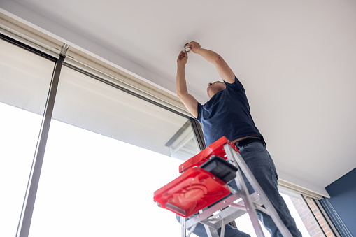 a master in a protective helmet for the maintenance of fire alarms, conducts an inspection in the residential sector