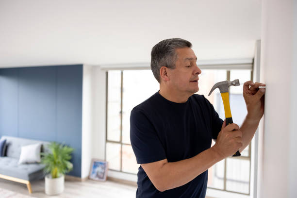 Man using a hammer to put a screw in the wall