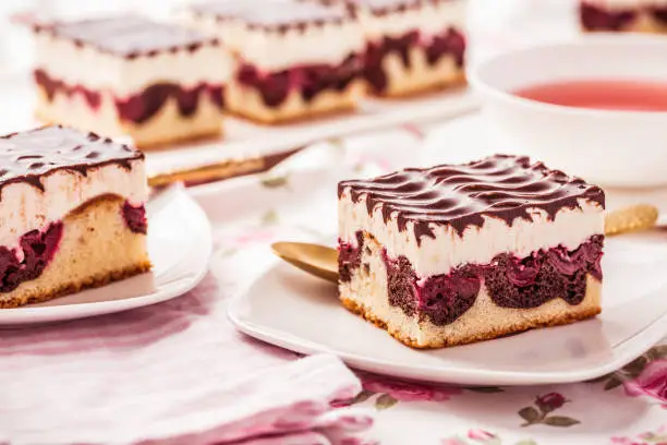 German cake Donauwelle (Danube waves) - vanilla and chocolate sponge cake with sour cherries, vanilla buttercream and chocolate icing with cup of tea