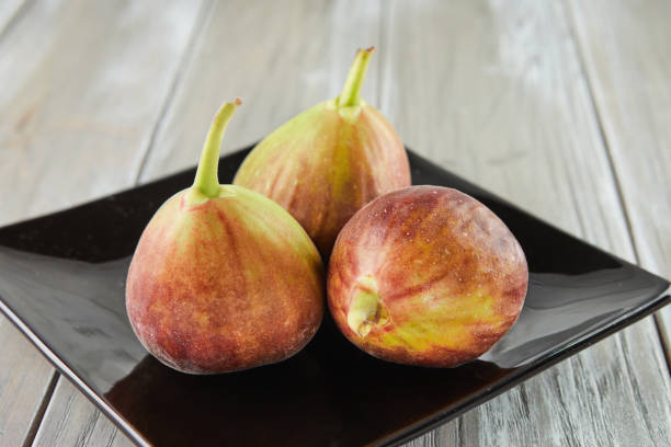 istock Fresh figs in black plate on wooden background 1408161057