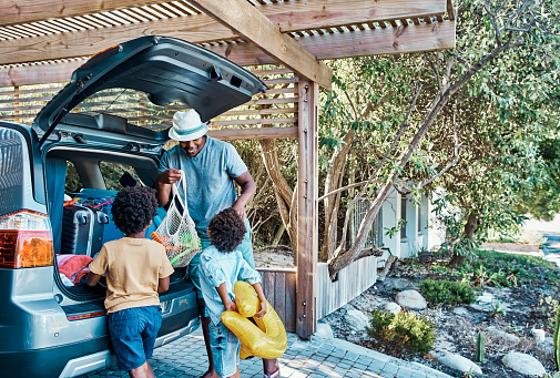 istock Excited black family packing their car trunk for a trip to the beach. Happy single dad and playful kids loading their boot for a summer vacation. Time to travel and have fun on a road trip together 1408161147
