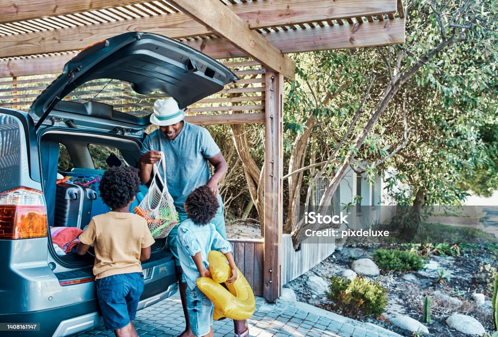 Excited black family packing their car trunk for a trip to the beach. Happy single dad and playful kids loading their boot for a summer vacation. Time to travel and have fun on a road trip together Car Stock Photo