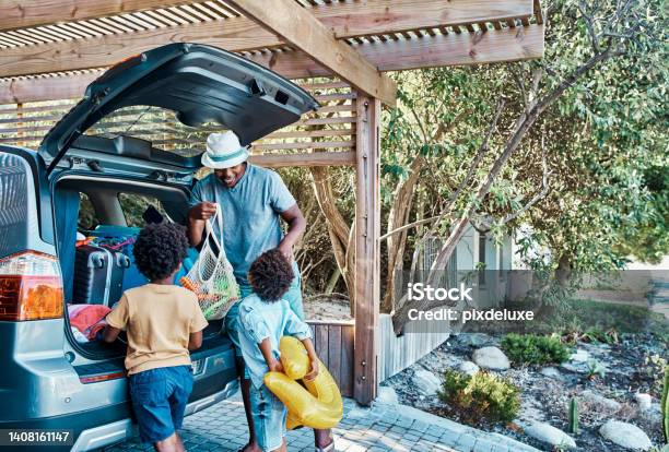 Excited Black Family Packing Their Car Trunk For A Trip To The Beach Happy Single Dad And Playful Kids Loading Their Boot For A Summer Vacation Time To Travel And Have Fun On A Road Trip Together Stock Photo - Download Image Now