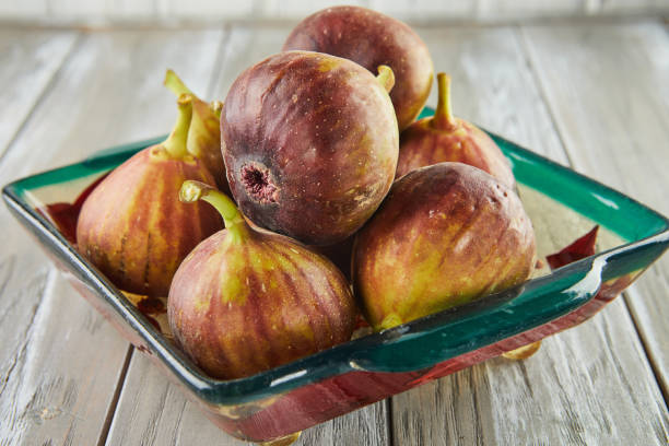 Fresh figs In green plate on wooden background
