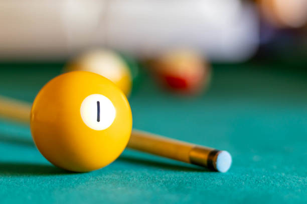 Woman concentrating on a precise pool shot, lining up the cue stick on green felt as she aims at the cue ball and target ball during a relaxed recreational game in a bar