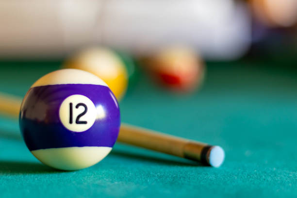 Billiard twelve ball on green tapestry and more balls in the backgrownd