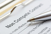 Blue ballpoint pen on a non compete contract. Noncompete contract is an agreement between employee and employer, not to enter into competition in subsequence business effort. Legal concept.