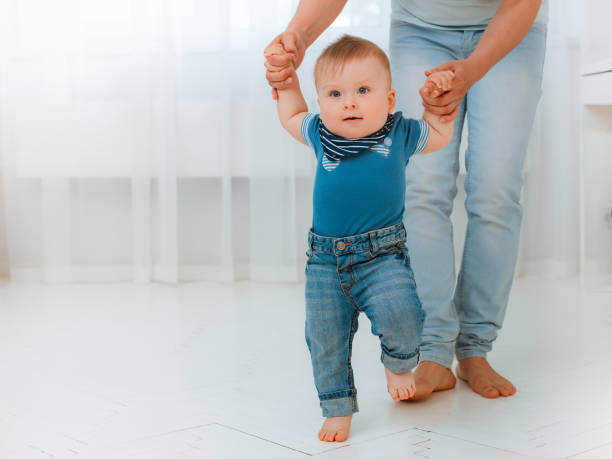 istock Baby taking first steps with mother's help at home 1408167165