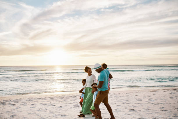 istock Parents bonding with their little sons while on holiday. Little siblings playing with their parents on vacation. Carefree african american family walking and having fun together on a sunset beach. 1408168028