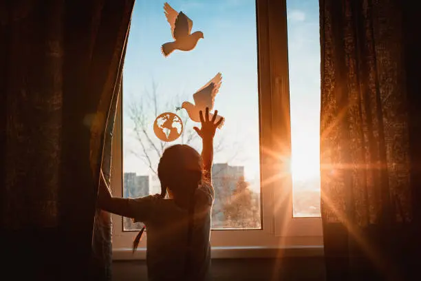 Photo of child stretches his hands sunlight outside window flying dove world with branch forces globe. concept peace world, no war, ecology