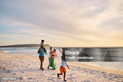 istock Young family walking on the beach together on the weekend. Loving parents on a walk with their children at the seashore during a vacation. Boy flying a plane and bonding with mom and dad on holiday 1408172327