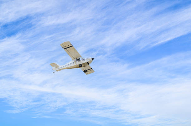 Light aircraft flying over blue sky Single engine ultralight plane flying in the blue sky with white clouds ultralight stock pictures, royalty-free photos & images